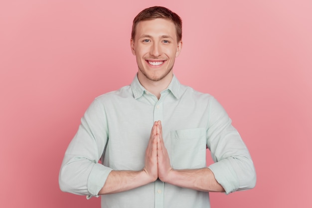 Portrait of cheerful attractive hopeful guy hands together toothy beaming smile please on pink background