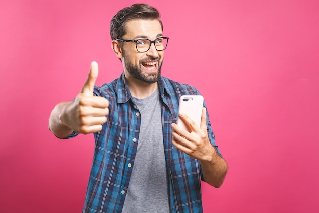 Portrait of a cheerful bearded man taking selfie and showing thumbs up gesture 