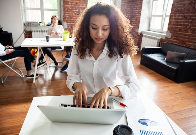 Portrait of cheerful business African-American lady working on laptop.