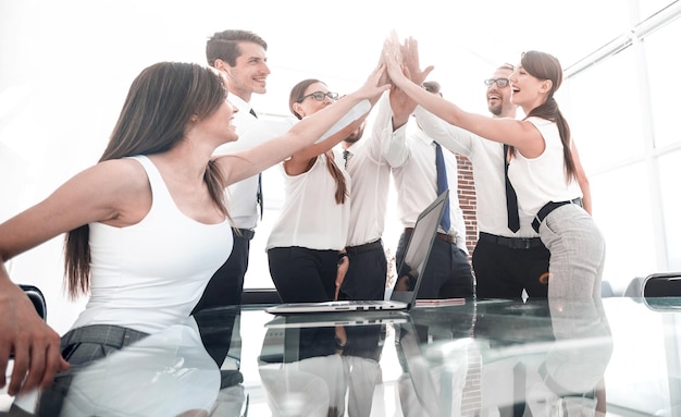 Portrait of a cheerful business team joining hands together in bright office