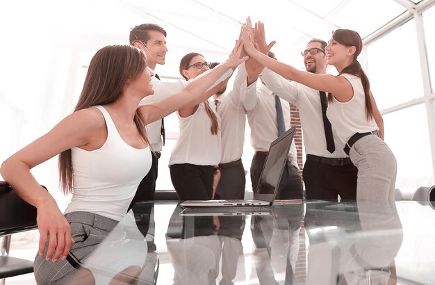 Portrait of a cheerful business team joining hands together in bright office