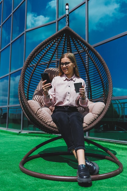 Portrait of a cheerful business woman in glasses enjoying a coffee break outdoors on a sunny day a successful woman manager talking on the phone while sitting against the background of the office