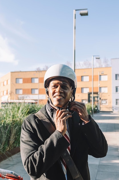 Portrait of cheerful businessman putting on helmet riding on an electric scooter