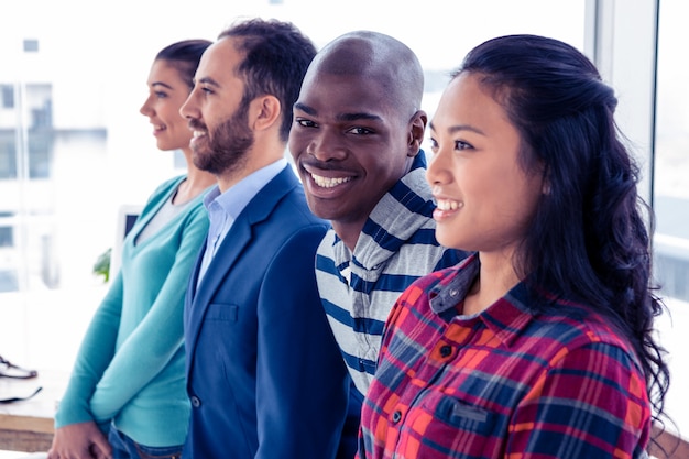 Portrait of cheerful businessman with colleagues standing in creative office