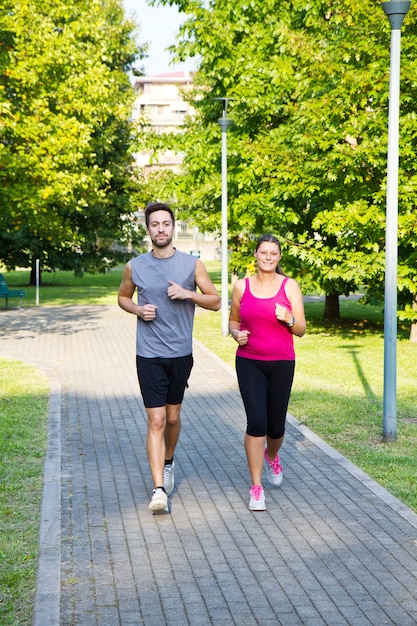 Portrait of cheerful caucasian couple running in the park