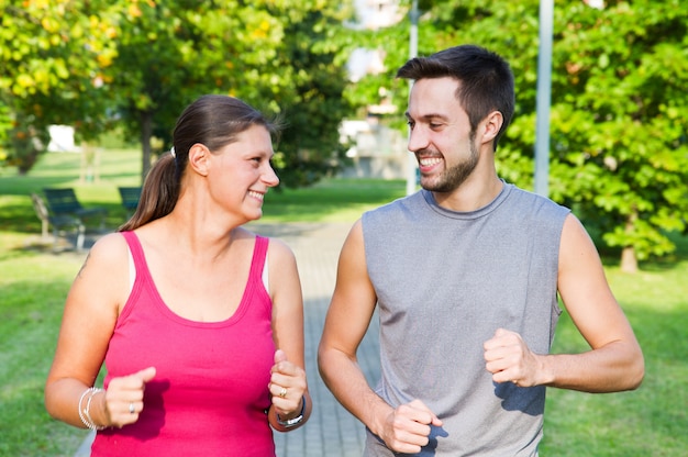 Portrait of cheerful caucasian couple running in the park