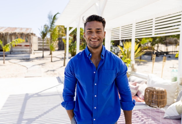 Photo portrait of cheerful caucasian young man wearing blue shirt standing at tourist resort, copy space. unaltered, vacation, handsome, lifestyle and enjoyment concept.