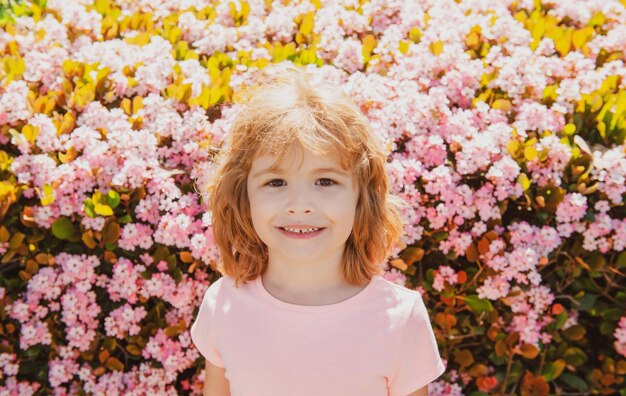 花の春の公園の背景に陽気な子供の肖像画かわいいうれしそうな男の子の子供