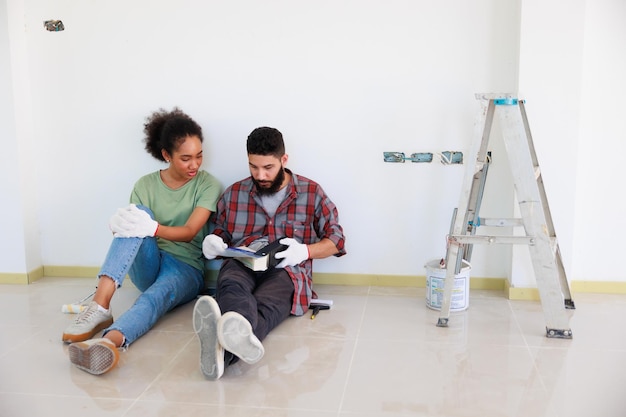 Portrait cheerful couple young man and black woman smiling\
during renovation in new apartment young happy family renovating\
house and planning bed room