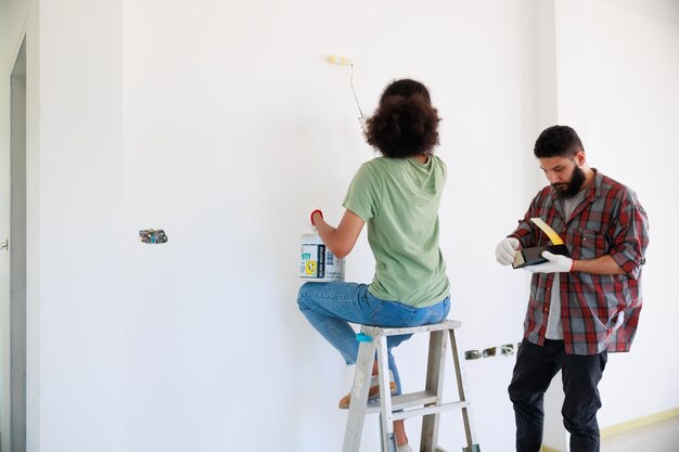 Portrait cheerful couple young man and black woman smiling\
during renovation in new apartment young happy family renovating\
house and planning bed room