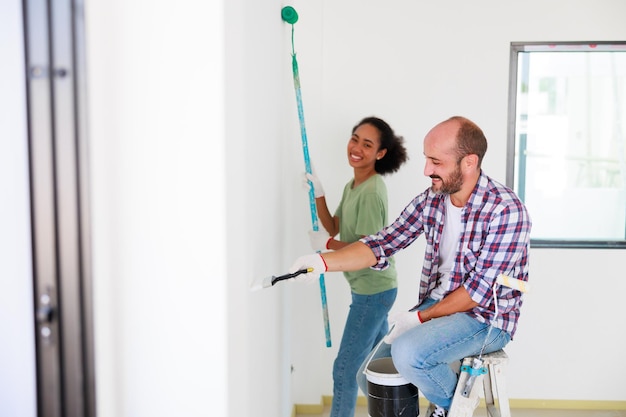 Ritratto coppia allegra giovane uomo e donna nera sorridente durante la ristrutturazione nel nuovo appartamento giovane famiglia felice che rinnova la casa e la pianificazione della camera da letto