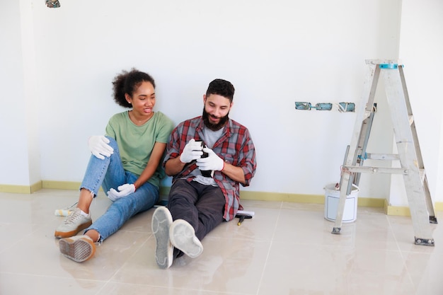 Ritratto giovane coppia allegra e donna di colore sorridente durante la ristrutturazione nel nuovo appartamento