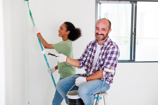 초상화 쾌활 한 커플 젊은 남자와 새 아파트에서 혁신 하는 동안 웃는 흑인 여성