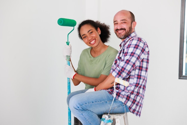 Портрет Веселая пара молодой мужчина и черная женщина улыбаются во время ремонта в новой квартире