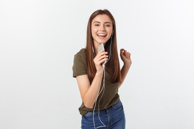 Portrait of a cheerful cute woman listening music in headphones and dancing isolated on a white .