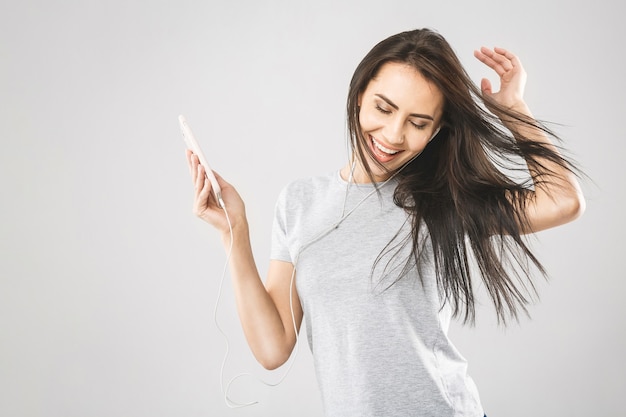 Photo portrait of a cheerful cute woman listening music in headphones and dancing