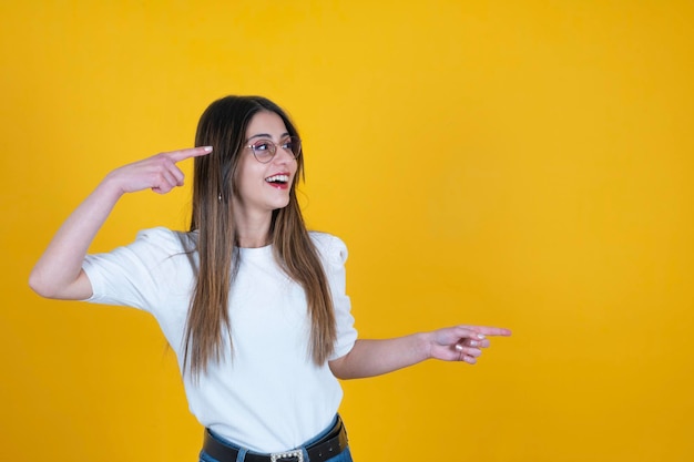 Portrait of cheerful excited caucasian woman pointing copy space standing over yellow backgroumd