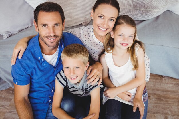 Portrait of cheerful family sitting by sofa