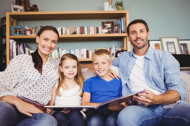 Portrait of cheerful family with book while sitting on sofa