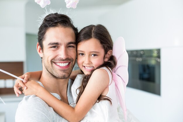 Portrait of cheerful father carrying daughter in fairy costume 