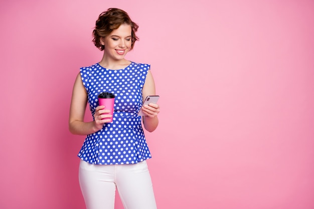 Portrait of cheerful focused girl drinking latte chatting online phone