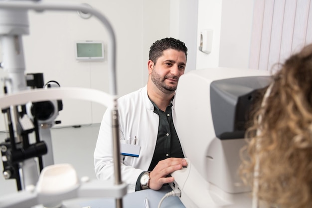 Photo portrait of a cheerful friendly eye doctor sitting in his office