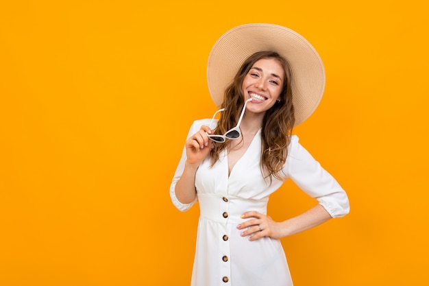 Portrait of a cheerful girl on an orange  in a hat