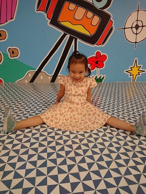 Foto ritratto di una ragazza allegra seduta sul pavimento a disegno