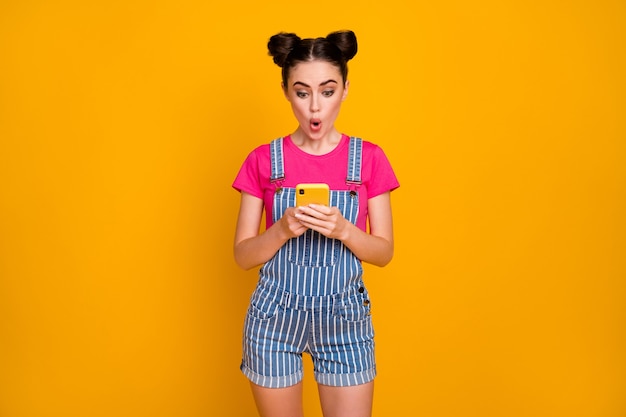 Portrait of cheerful girl use cell phone wireless connection on yellow background