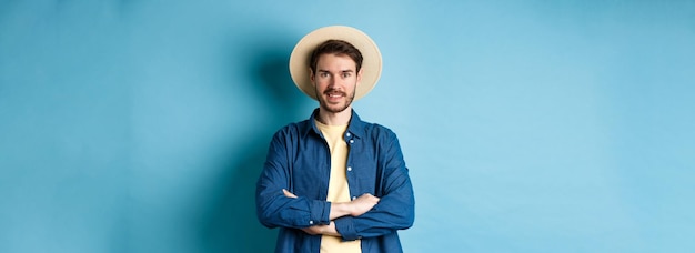 Portrait of cheerful guy going on vacation in straw summer hat cross arms on chest and smiling looki