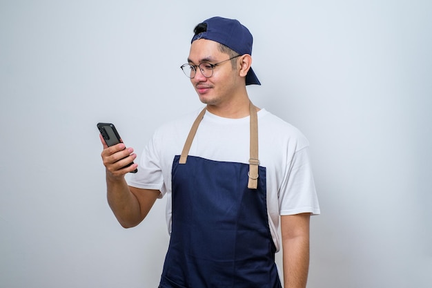 Portrait of cheerful handsome barista looking ahead and holding smartphone