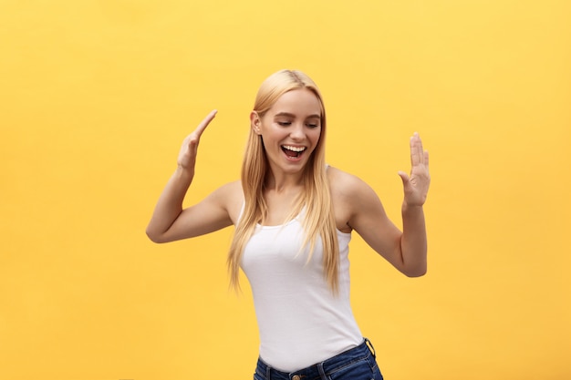 Photo portrait of a cheerful happy girl student while dancing isolated over yellow background