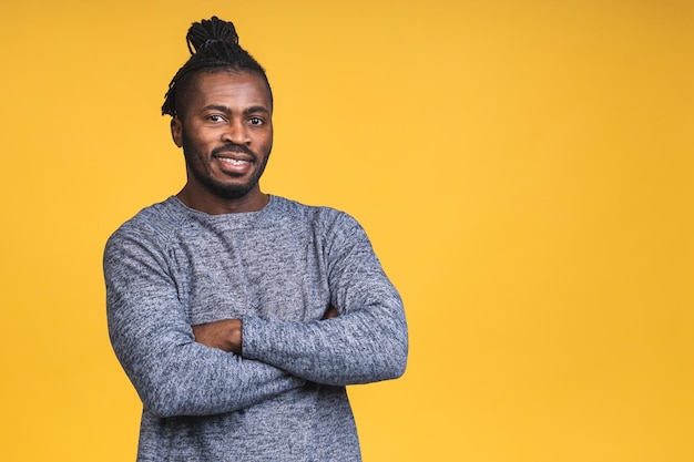 Portrait of a cheerful happy smiling young african american black man standing isolated over yellow background.