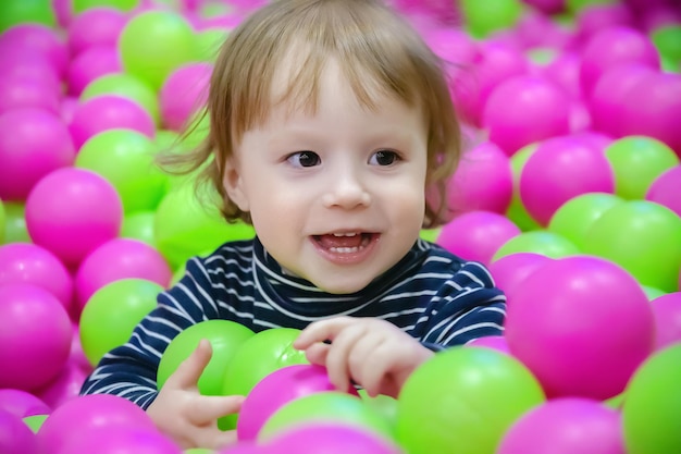 Ritratto di bambino allegro che gioca con palline colorate concetto di giorno dei bambini primo piano