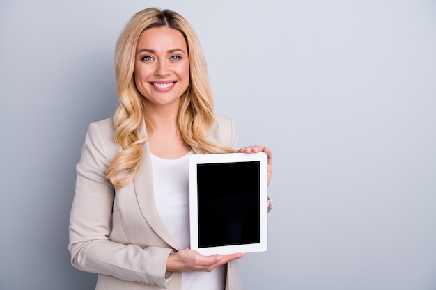 Portrait of cheerful lady holding in hands demonstrating tablet