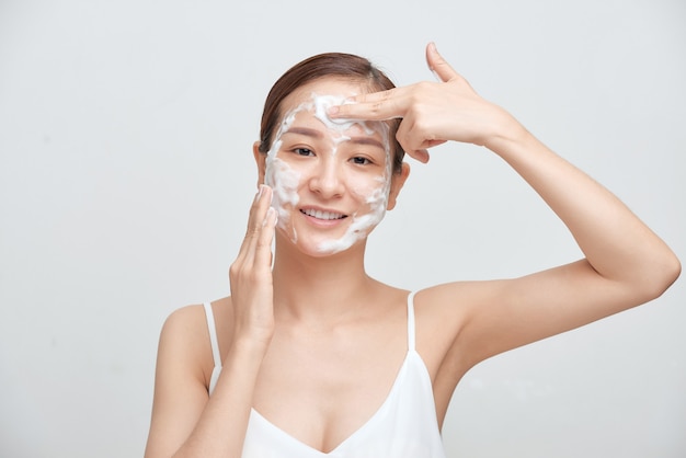 Portrait of cheerful laughing woman applying foam for washing on her face.