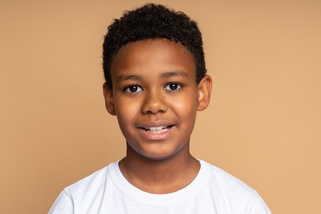 Portrait of cheerful little boy with curly hair in Tshirt smiling funny and carefree