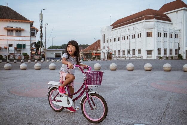 A portrait of a cheerful little girl on a bicycle in the city