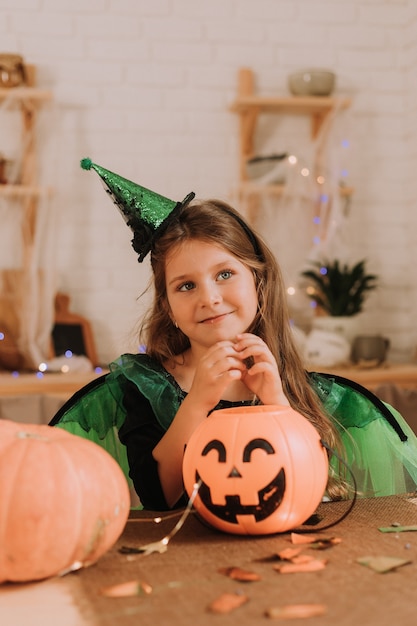 カボチャと燃えるろうそくとハロウィーンの衣装を着た陽気な少女の肖像画