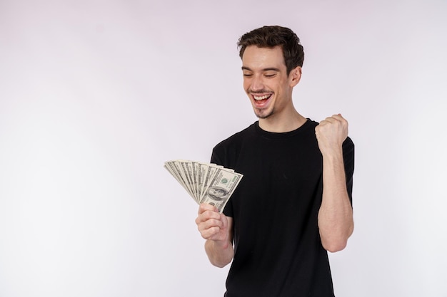 Ritratto di un uomo allegro in possesso di banconote da un dollaro e facendo il gesto del vincitore stringendo il pugno su sfondo bianco