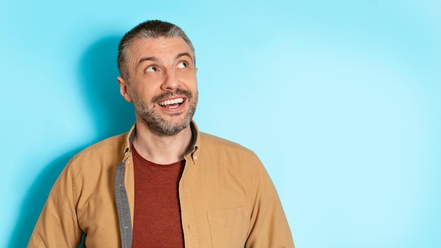 Portrait of cheerful man posing looking aside on blue background