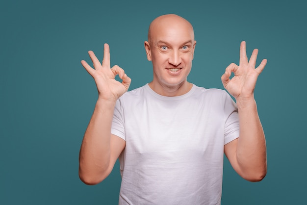 Photo portrait of a cheerful  man showing okay gesture isolated on the blue background