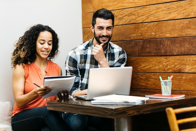 Photo portrait of cheerful man using laptop while sitting by woman at table