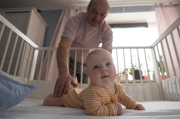 Portrait of a cheerful mature grandfather playing with grandson at the bedroom