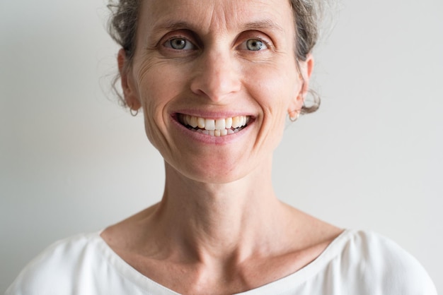 Portrait of cheerful mature woman against wall