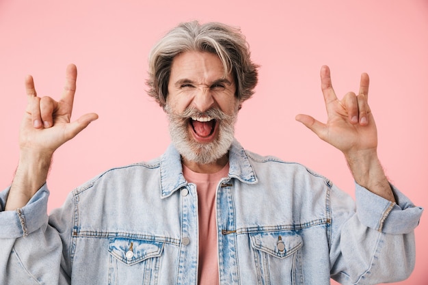 Portrait of a cheerful middle aged man wearing casual outfit standing isolated, showing horns up gesture