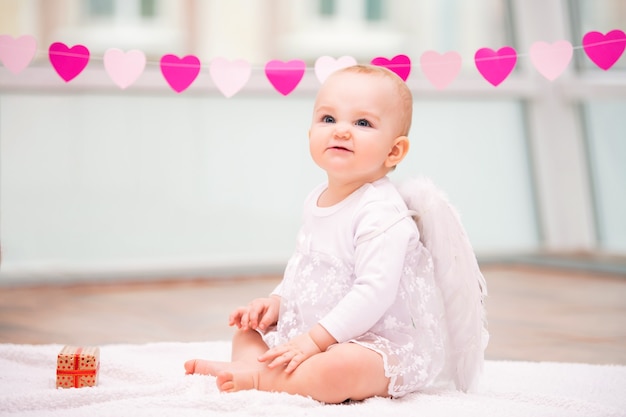 Portrait of a cheerful mischievous baby with white angel wings