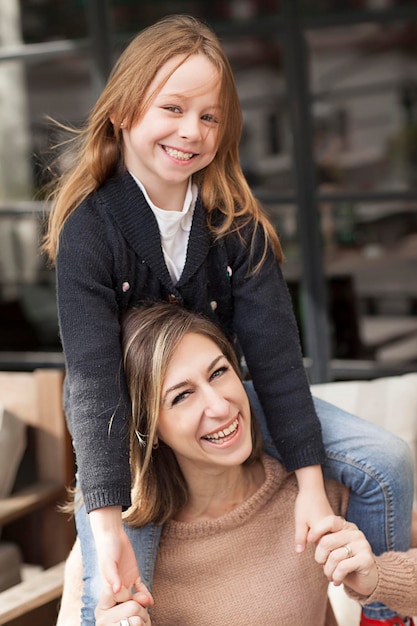 Photo portrait of cheerful mother sitting with daughter on sofa