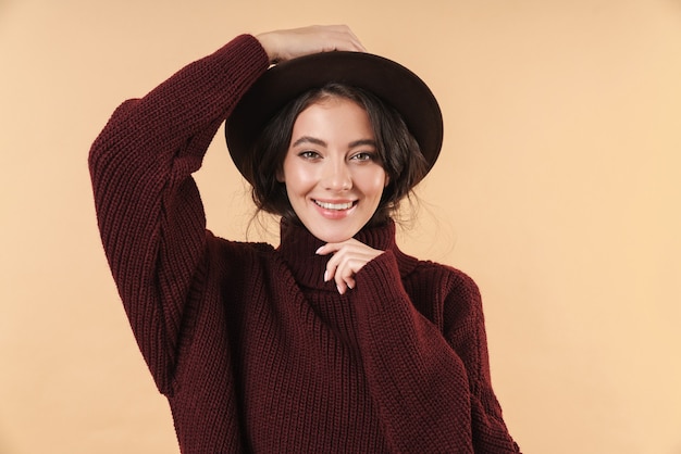 Portrait of cheerful optimistic cute happy young brunette woman posing isolated on beige wall.