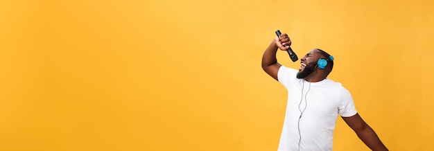 Portrait of cheerful positive chic handsome african man holding microphone and having headphones on